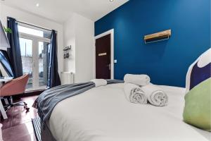 - une chambre avec un grand lit et un mur bleu dans l'établissement Lovely 2-bedroom rental unit in Greater London, à Hanwell