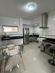 a large kitchen with a table and a refrigerator at APARTAMENTO IMPERIAL IV (COMPLETO) in Castanhal