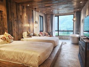 two beds in a room with wooden walls and windows at Mogan Tingshan Hotel in Deqing