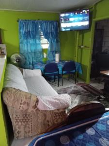 1 dormitorio con cama, mesa y TV en Caribb Home and Taxi Service, en Bridgetown