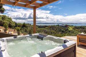 bañera de hidromasaje en una terraza con vistas al océano en Nikau Estate, Oneroa - Be My Guest, en Matiatia Bay