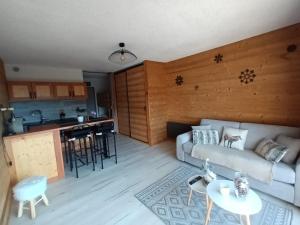 a living room with a couch and a kitchen at Appartement montagne LE FLOCON in Saint-Michel-de-Chaillol