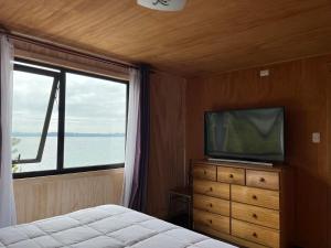 a bedroom with a bed and a tv and a window at Departamento con vista al Mar in Ancud