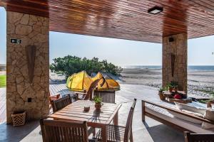 eine Terrasse mit einem Tisch und Stühlen am Strand in der Unterkunft Vila Cangalha in Camocim