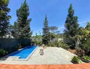 un patio trasero con piscina y árboles en The Joglo Villa, en Bandung