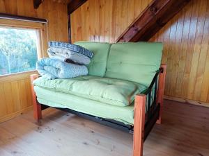 un sofá verde sentado en una habitación con ventana en cabañas los maites, en Chonchi