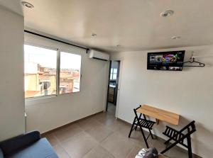 un soggiorno con tavolo e TV a parete di Apartamentos con baño privado frente al metro L5 Barcelona-Hospitalet a Hospitalet de Llobregat