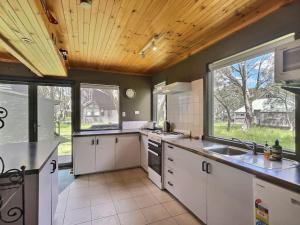 cocina con armarios blancos y techo de madera en Glacier Chalet, en Dinner Plain