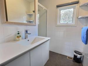 Un baño blanco con lavabo y espejo. en Glacier Chalet, en Dinner Plain 6 fotos más