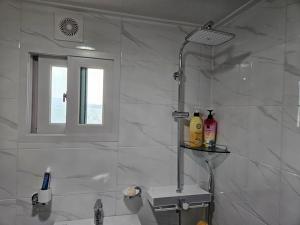 a white bathroom with a shower and a sink at Yonghyun's house in Wando
