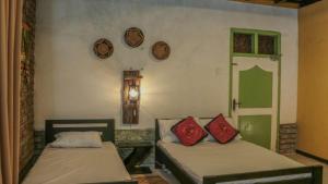 2 camas en una habitación con relojes en la pared en SHADOW MASK BUNGALOW en Pattipola