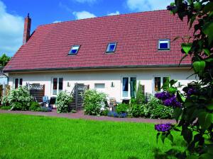 Casa blanca con techo rojo y patio en Holiday apartment in the Mecklenburg Lake District en Buchholz