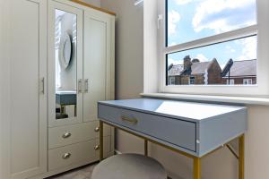 a dressing room with a blue dresser and a window at Chic Retreat Residences: 3 BD Haven - Sleeps 10 in London