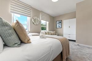 a white bedroom with a large bed and windows at Chic Retreat Residences: 3 BD Haven - Sleeps 10 in London
