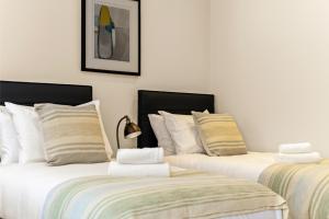 dos camas sentadas una al lado de la otra en una habitación en Chic Retreat Residences: 3 BD Haven - Sleeps 10 en Londres