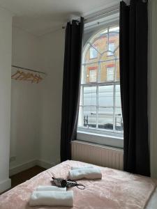 a bedroom with a bed with two towels and a window at Private Bedrooms in Camden Town, Central London (10) in London