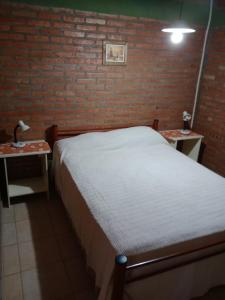 a bedroom with a bed and two tables with lamps at los nidos habitaciones in Villa Cura Brochero