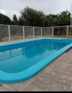 a blue swimming pool with a fence around it at Los nidos 3 in Villa Cura Brochero