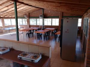 a restaurant with tables and chairs and a refrigerator at Los nidos 3 in Villa Cura Brochero