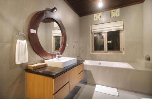 a bathroom with a sink and a mirror and a tub at Tegal Sari Accommodation Ubud in Ubud