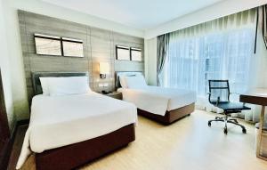 ein Hotelzimmer mit 2 Betten und einem Schreibtisch in der Unterkunft Citrus Sukhumvit 11 by Compass Hospitality in Bangkok