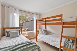 a bedroom with two bunk beds and a window at Salty Air Cottage in Bream Creek