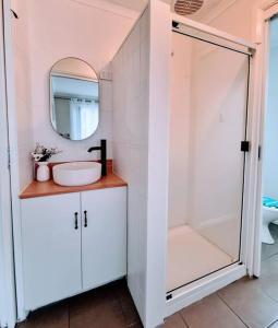 a white bathroom with a sink and a mirror at Salty Air Cottage in Bream Creek