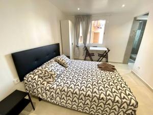 1 dormitorio con 1 cama con edredón blanco y negro en Apartamentos con baño privado frente al metro L5 Barcelona-Hospitalet, en Hospitalet de Llobregat