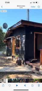 una pequeña casa negra con porche y puerta en Hermosa cabaña en Valdivia, en Valdivia