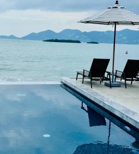 two chairs and an umbrella next to a swimming pool at Baan Haad Ngam Boutique Resort in Chaweng