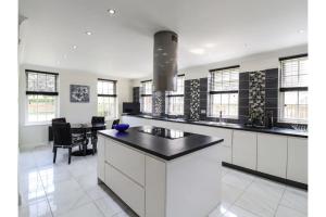 a kitchen with white cabinets and a black counter top at Luxurious 6 Bedroom Villa with Pool Sleeps 12 in Canvey Island