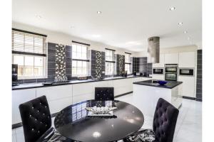 a kitchen with a round table and black chairs at Luxurious 6 Bedroom Villa with Pool Sleeps 12 in Canvey Island
