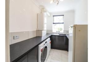 een witte keuken met een wasmachine en droger bij Luxurious 6 Bedroom Villa with Pool Sleeps 12 in Canvey Island