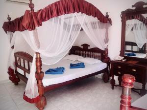 a bedroom with a wooden canopy bed with curtains at River View Banquet & Resort in Wadduwa