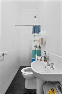 a white bathroom with a toilet and a sink at The Pyrmont Budget Hotel in Sydney