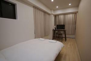 a bedroom with a bed and a desk and a television at Tokyo Guest 浜町 in Tokyo