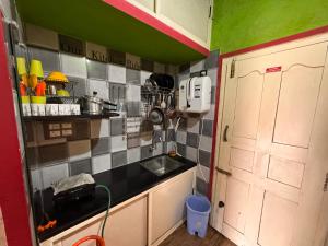 een kleine keuken met een wastafel en een deur bij Thelmas Croft in Madikeri