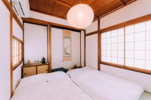 two beds in a room with windows at One Harajuku: Private Oasis in Tokyo