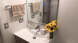 ein Badezimmer mit einem Waschbecken mit einem Spiegel und einer Vase aus Blumen in der Unterkunft Dpto 3P - Barrio Italia - Santiago de Chile in Santiago