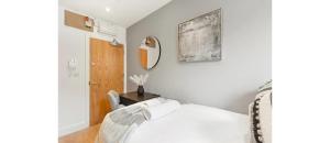 een witte slaapkamer met een bed en een spiegel bij The *Best* Airbnb for Transport in London! Promise in Londen