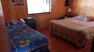 - une chambre avec deux lits, une fenêtre et un lit dans l'établissement El Paraíso de Los Cisnes, à Quellón