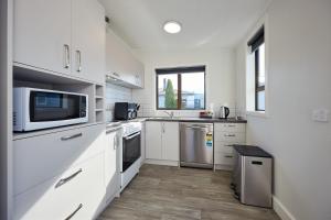 a kitchen with white cabinets and a microwave at Extremely Central in Kaikoura