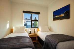 two beds in a room with a window at Central | Beach Nearby | Parking - KK27622 in Kaikoura +3 photos