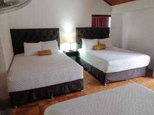 two beds in a hotel room with two beds at Global Airport Inn in Guatemala