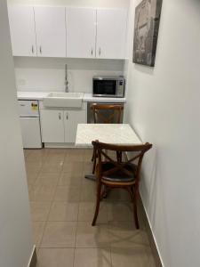 eine Küche mit weißen Schränken, einem Tisch und einem Stuhl in der Unterkunft Broadway Apartment in West Wyalong