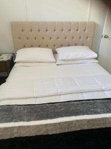 a large white bed with a padded headboard and white pillows at Broadway Apartment in West Wyalong
