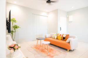 a living room with an orange couch and a stool at Zenstay Sdn Bhd in Bukit Mertajam