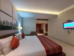 a bedroom with a large bed with a tv on the wall at Orbit Hotel in Bāghdogra