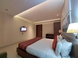 a hotel room with a bed and a tv at Orbit Hotel in Bāghdogra