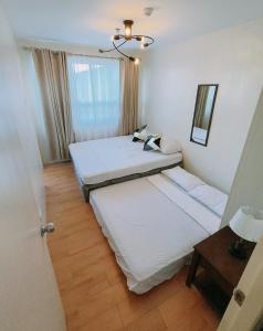 a bedroom with two beds and a table and a window at Davao Condo 2BR Pool Wifi Netflix in Davao City
